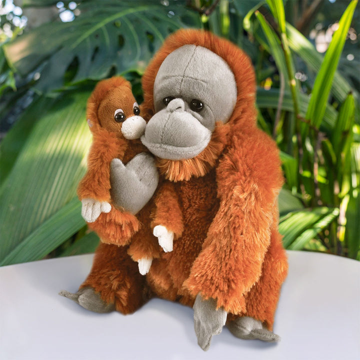 The Orangutan + Baby Adoption Kit includes adult and baby plush orangutans sitting together with leafy decor, creating a jungle scene—ideal for inspiring interest in Sumatran orangutans or starting an animal adoption journey.