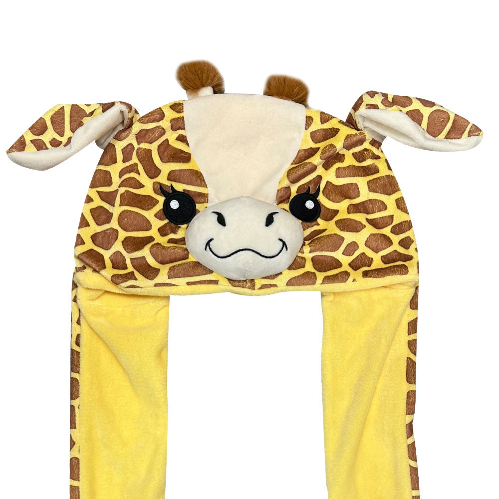 The Giraffe Pop Ears Hat features a plush giraffe design with a smiling face, two ears, brown ossicones, yellow and brown patterned recycled velboa fabric, and long hanging sides.