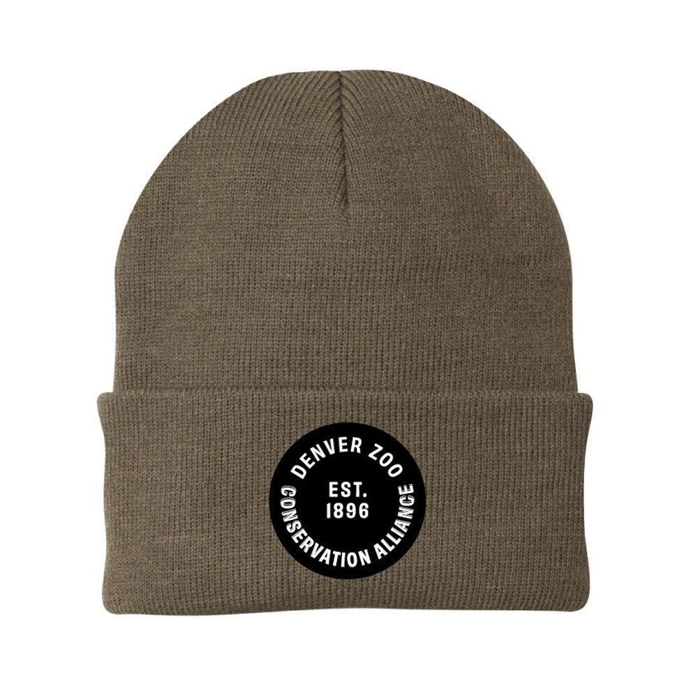 The DZCA Cold Weather Beanie is a brown knit unisex hat with a folded cuff, featuring a black circle patch reading "Denver Zoo Conservation Alliance Est. 1896" in white—ideal for stylish warmth in cold weather.