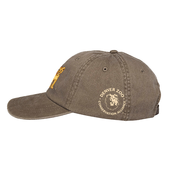 The DZCA Lion Cub Embroidered Cap features a playful lion cub on the front and the Denver Zoo Conservation Alliance lion head logo on the side, supporting the African Lion Species Survival Plan and celebrating lion pride.