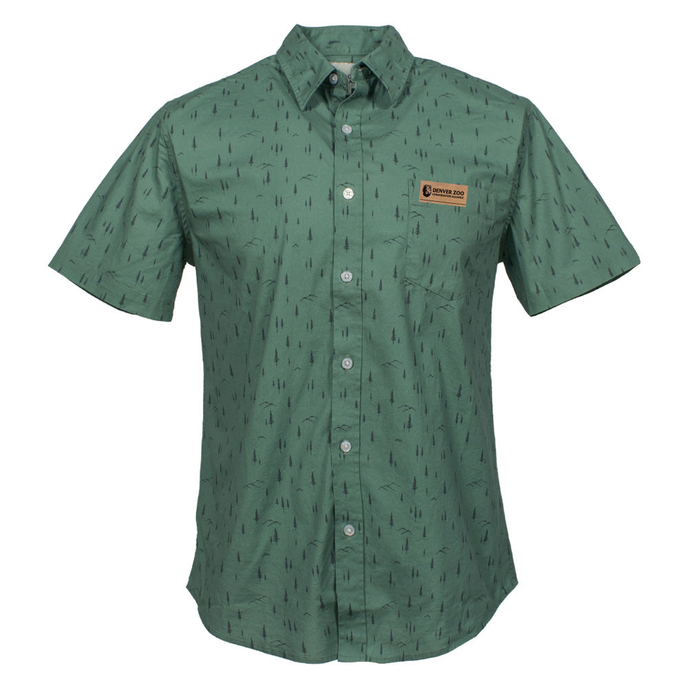 The DZCA x Jack and Sage Tree Button-Up Shirt is a green short-sleeve dress shirt with a black tree pattern, chest pocket, tan patch above the pocket, classic collar, and white buttons for a timeless, nature-inspired style.