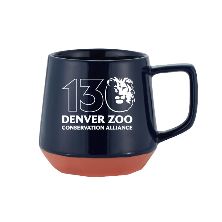 The DZCA 130th Anniversary Mug is a navy blue ceramic mug with a matte red base, featuring the Denver Zoo Conservation Alliance lion logo and “130” in white—a unique collectible celebrating the milestone.