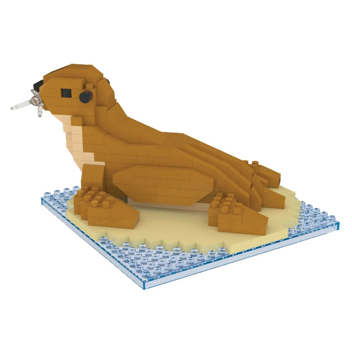 The Sea Lion Mini Building Blocks set includes a brown sea lion figure with a raised head, black eyes, and a gray fish in its mouth, displayed on a tan and blue base. Made from non-toxic ABS material for safe building fun.