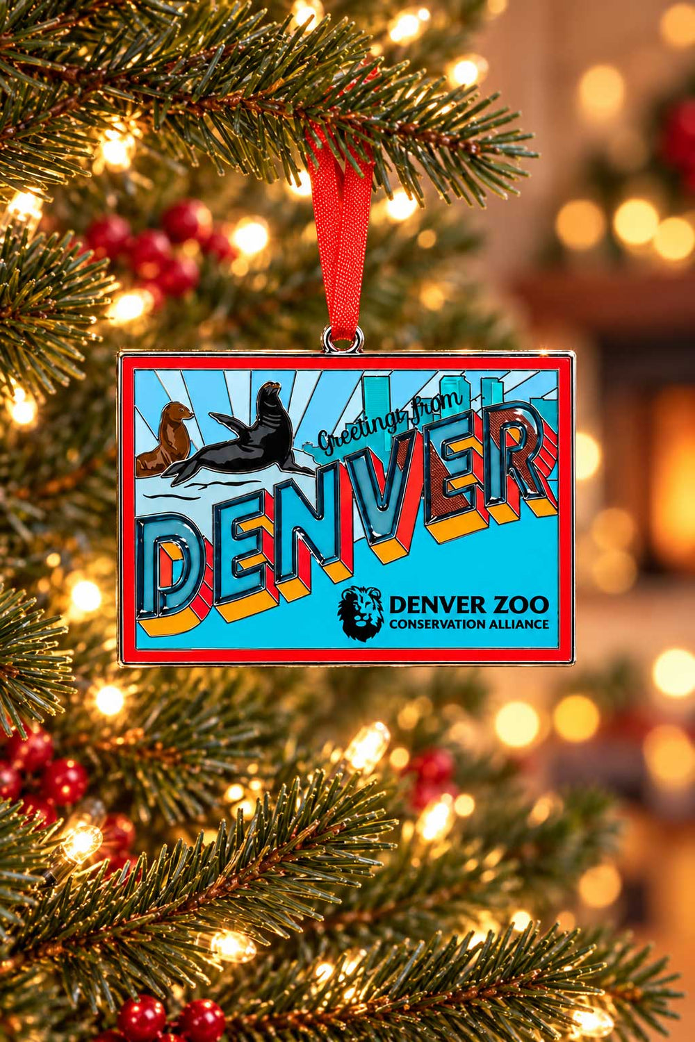 DZCA Sea Lions Greeting Stained Glass Ornament hanging on a Christmas tree, featuring a rectangular shape with two sea lions, the word DENVER in bold letters, and the Denver Zoo Conservation Alliance logo below.