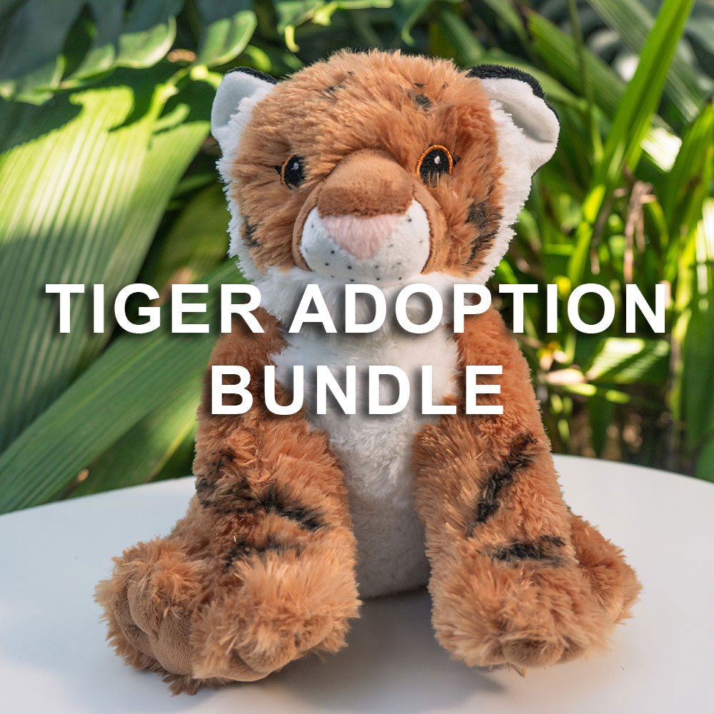 A plush tiger toy sits on a white surface with green plants behind it, showcasing the Tiger Adoption Bundle. The words TIGER ADOPTION BUNDLE appear in bold white letters across the image.