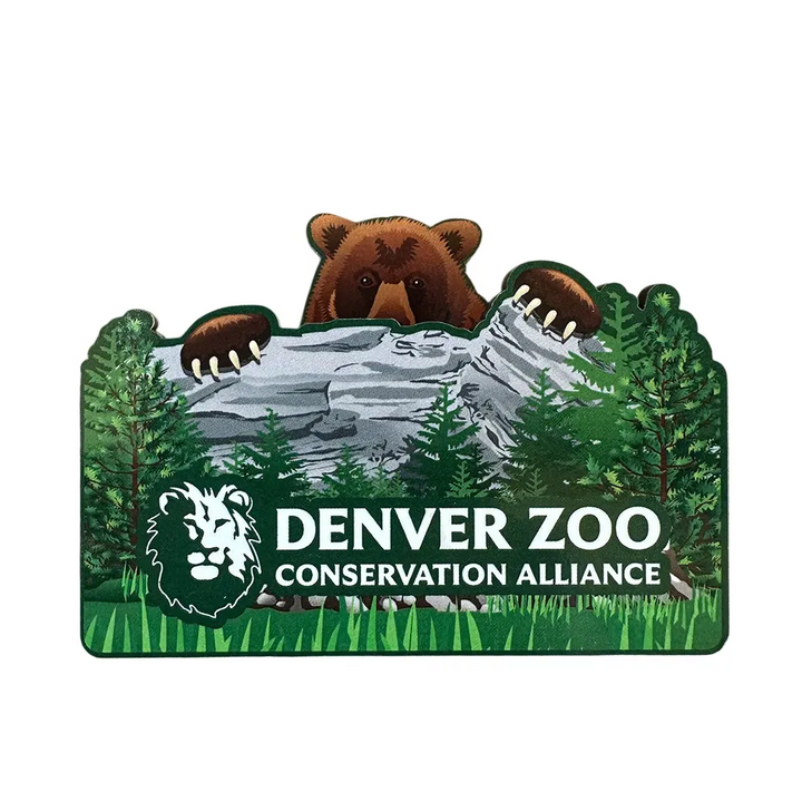 The DZCA Bear Pop-up Magnet features a bear peeking over a rocky ledge amid trees, with "Denver Zoo Conservation Alliance" and a lion head logo—an ideal wildlife-themed décor piece for animal lovers.