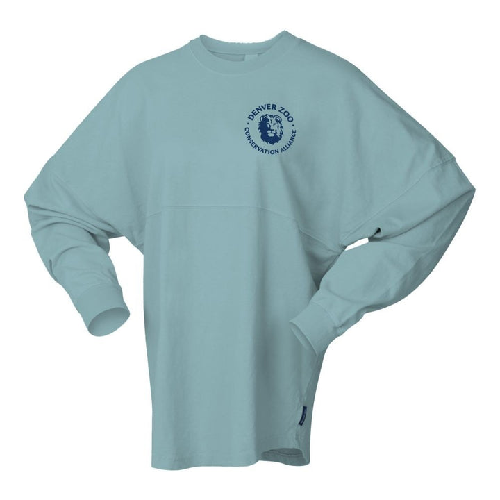 The DZCA Sea Lion Spirit Jersey is a light blue long-sleeve crewneck with a dark blue circular Denver Zoo Conservation Alliance logo and lion’s head, celebrating marine mammal conservation in Sea Lion Spirit Jersey style.