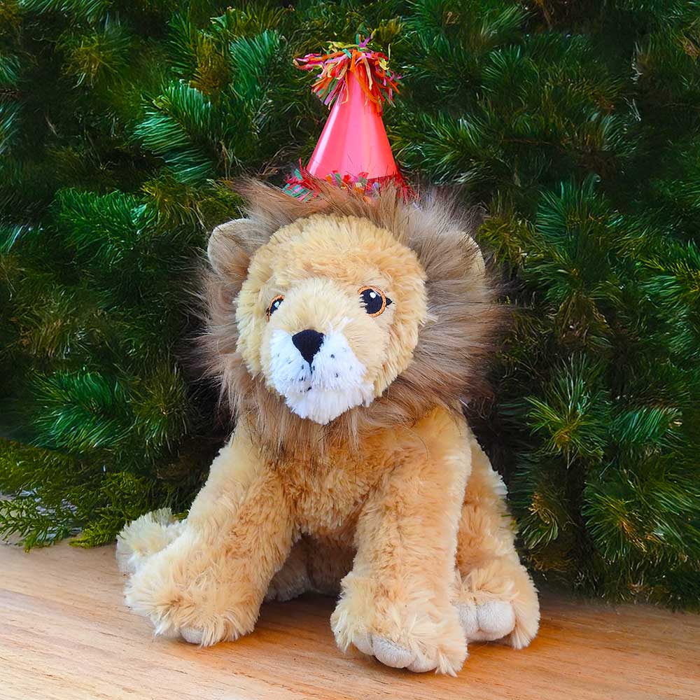 A plush lion in a red party hat sits on wood before green leaves—an ideal scene for the Birthday Adoption Bundle.